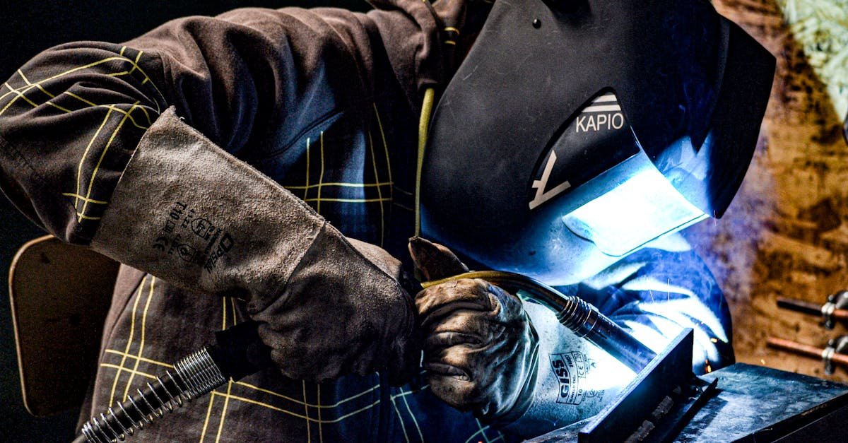 A male welder operates in a factory setting, using protective gear for safety.
